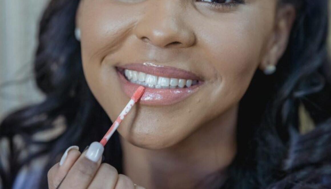 Lady putting lip gloss on and smiling wide