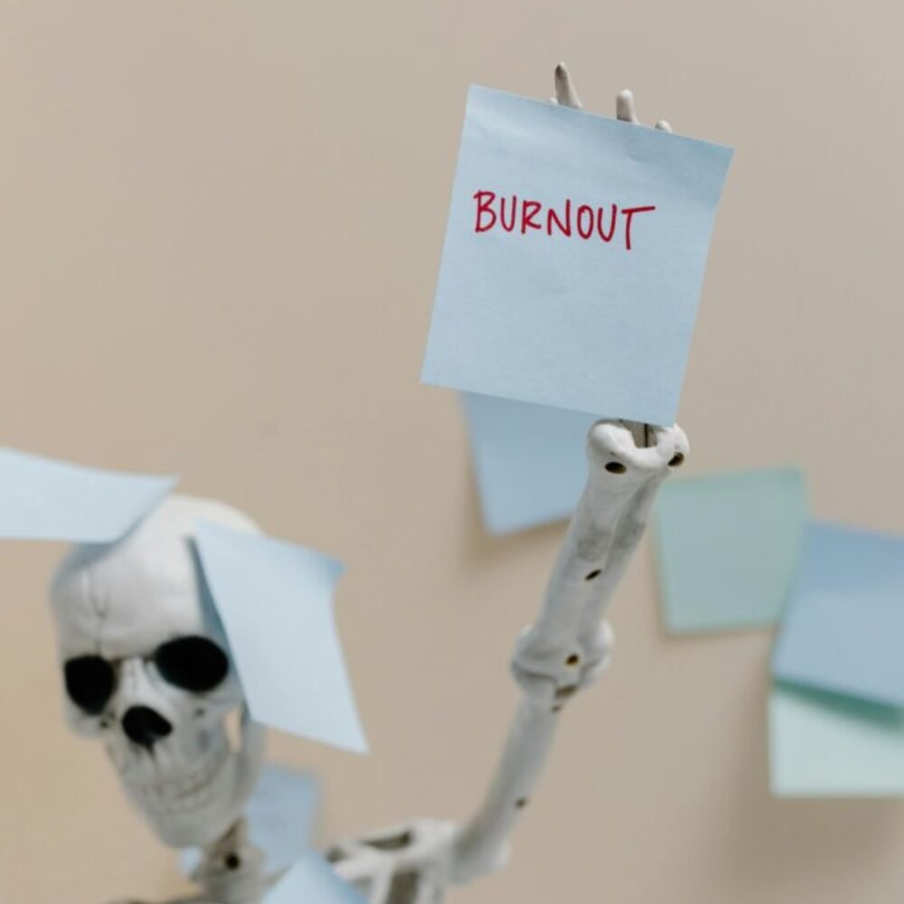Skeleton holding a burnout sign, probably a corporate employee